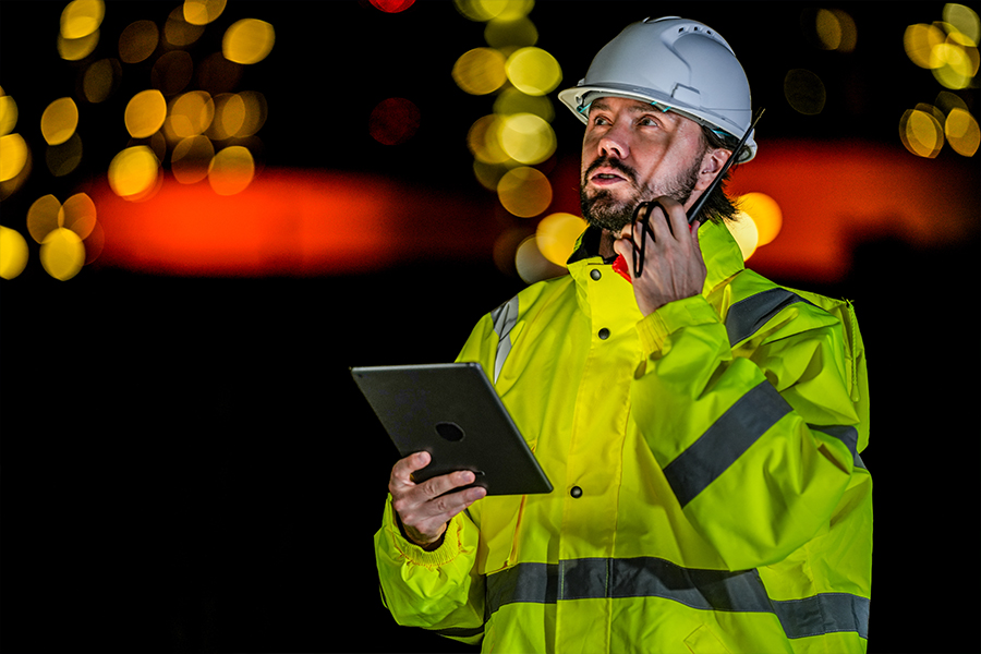 Emergency management professional using a tablet and radio to coordinate operations, illustrating technology, communication, and community resilience planning.