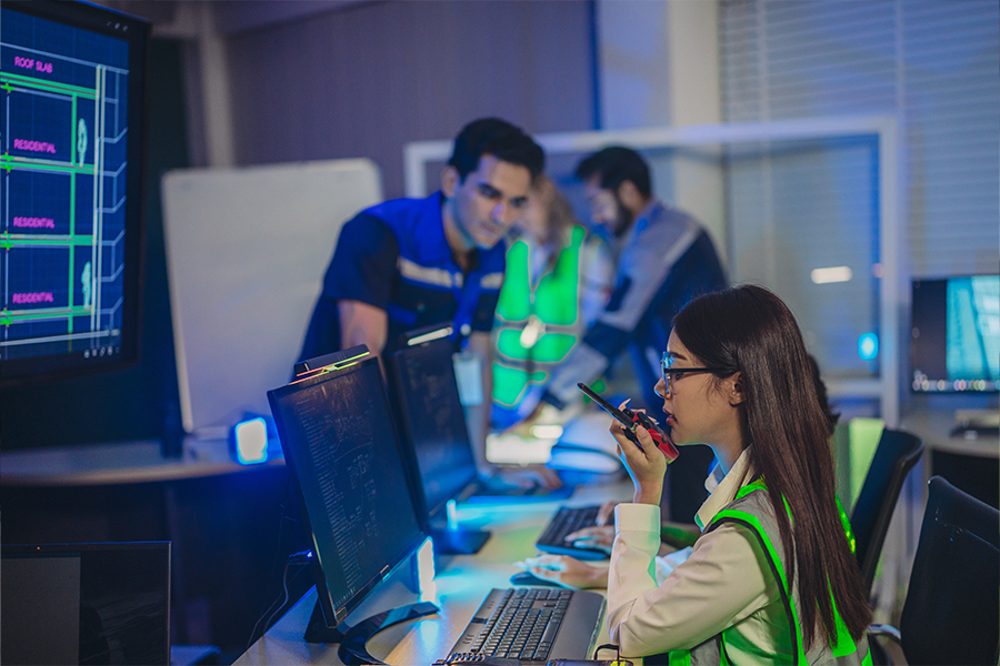 Emergency operations center staff monitoring computer systems and communicating by radio during an emergency response coordination exercise.