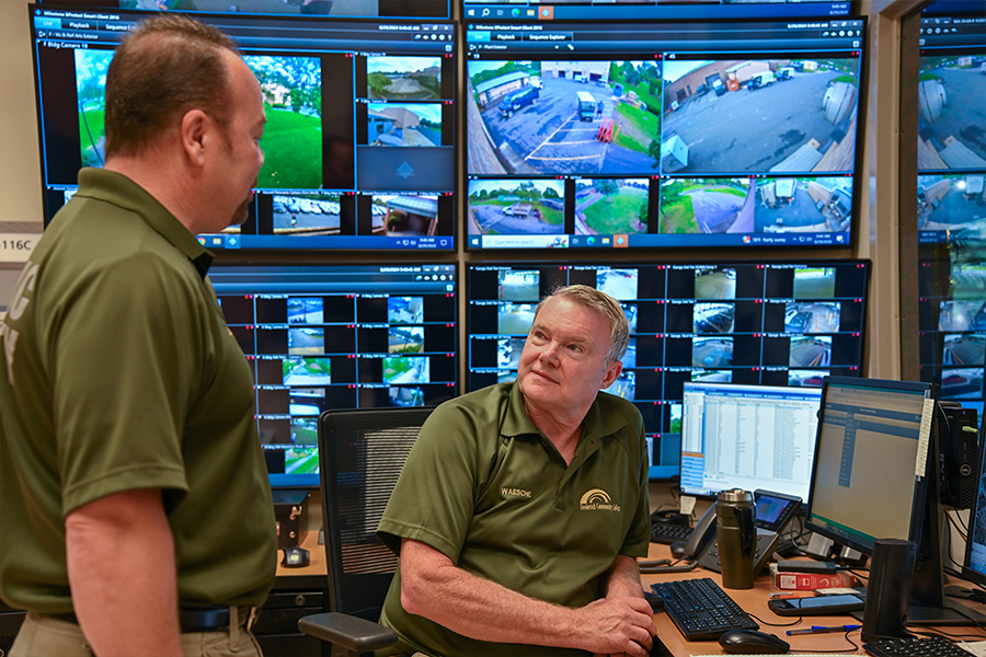 Emergency operations center personnel monitoring surveillance and security systems, with multiple screens displaying live camera feeds and operational data.