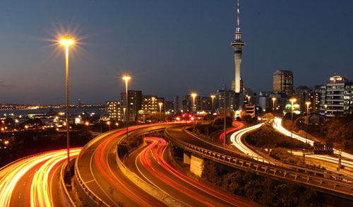 City skyline at dusk with illuminated highways and light trails from traffic, representing urban infrastructure, connectivity, and community resilience.
